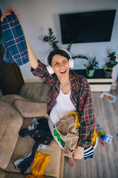 Smiling woman enjoying music while doing laundry and cleaning at home