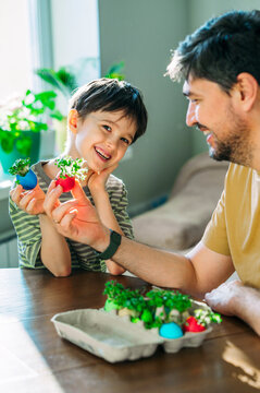 Family showing Easter eggshells with growing microgreens indoors