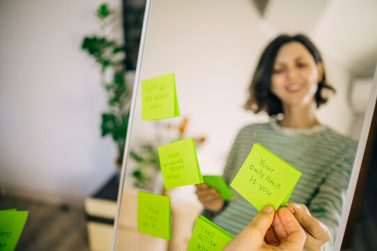 Smiling reflection in mirror reading positive affirmation note