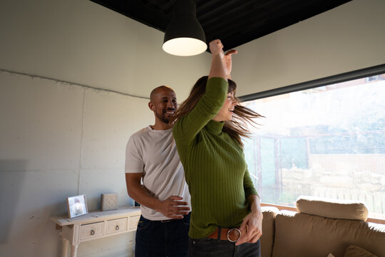 Couple laughing and dancing with joy in sunlit living room