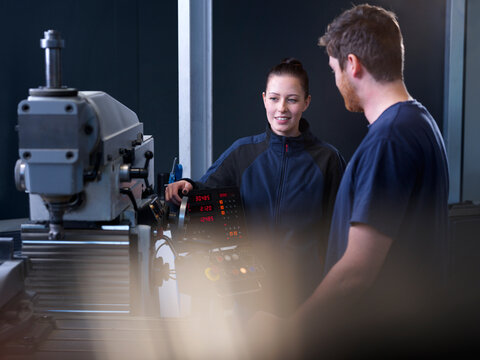 Engineers discussing near CNC machine at factory