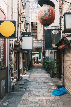 Empty narrow alley with traditional lantern and shop signs in Osaka