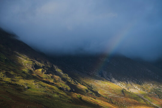 Sunlit mountain slope and rainbow in the Scottish Highlands