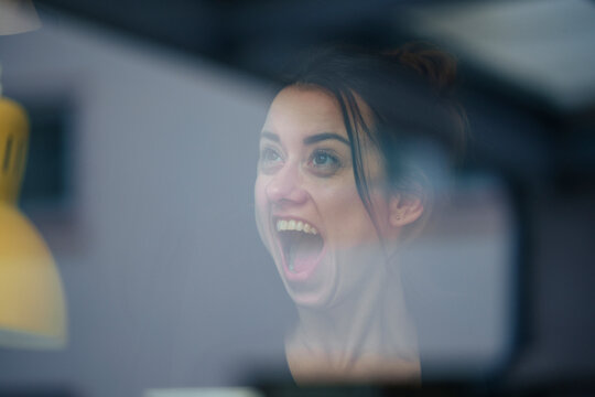 Businesswoman shouting seen through window at home
