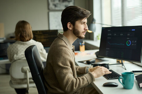 Manager analyzing statistics at computer desk with colleague