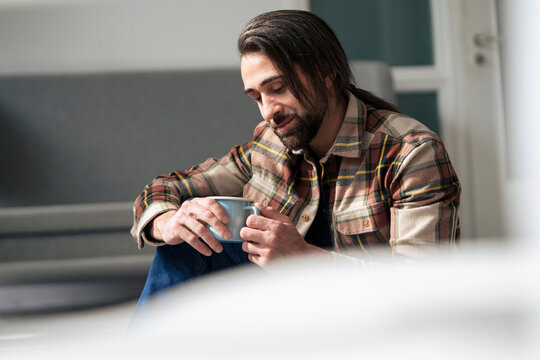 Thoughtful businessman holding coffee mug in break at office