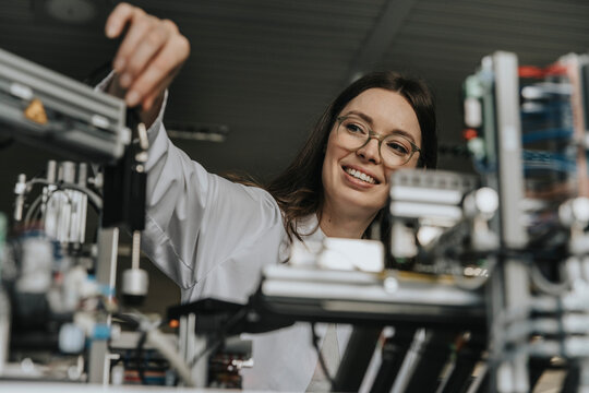 Scientist in laboratory adjusting machine during research experiment