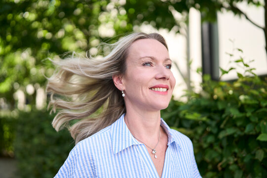 Smiling woman running outdoors with wind in hair in urban area