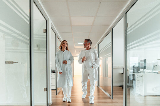 Medical colleagues walking and discussing in modern hospital corridor