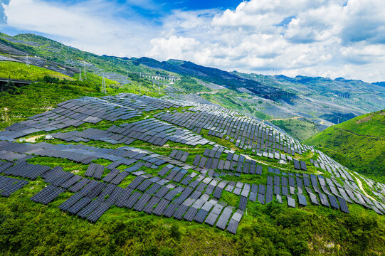 Aerial view of large-scale solar farm with photovoltaic panels on green mountain slopes