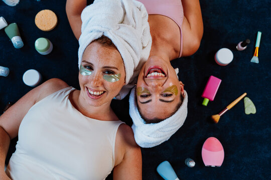 Two happy women lying down, enjoying beauty treatment with under eye patches