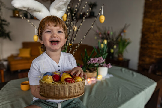 Child with bunny ears holding basket of Easter eggs