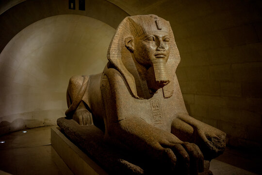 Ancient Egyptian Great Sphinx of Tanis displayed inside the Louvre Museum in Paris, France. The monumental granite sculpture is shown in a grand gallery with arched ceilings, highlighting its historic