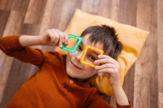 Happy child playing indoors with magnetic toy looking at camera