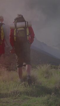 Vertical video: Travel hiker checking map to navigate and climbing ridge, red haze sweeping legs
