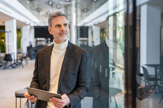 Businessman in an office holding a tablet and looking away