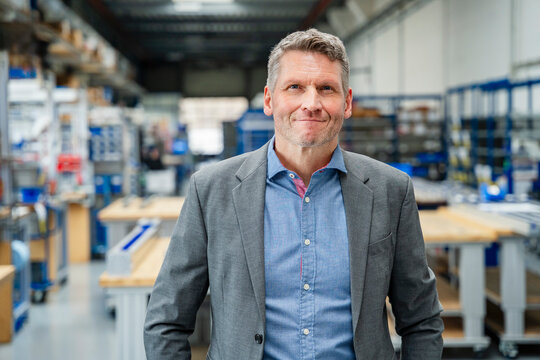 Smiling manager standing in bright production hall