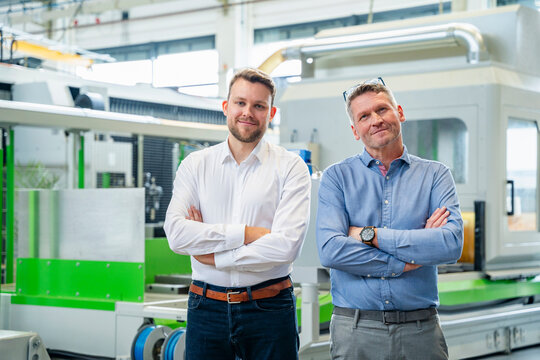 Managers standing in a production hall with arms crossed