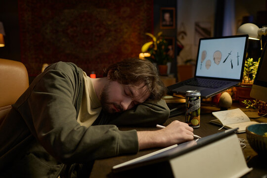 Exhausted freelance digital artist sleeping at desk during night