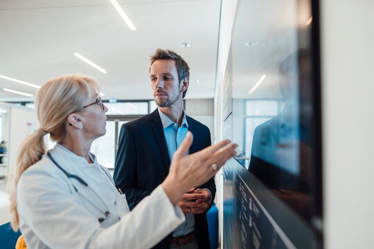 Mature doctor discussing with man over computer screen in hospital