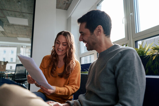 Happy business people having discussion over document in office