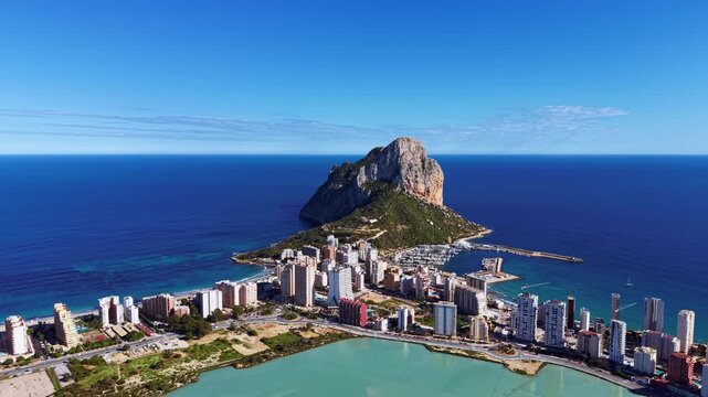 Calpe, Spain coastal city with Penon de Ifach rock formation rising above the Mediterranean Sea, featuring marina, high-rise buildings and turquoise lagoon