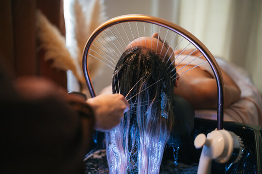 Close up of professional hands applying water and massaging scalp in spa