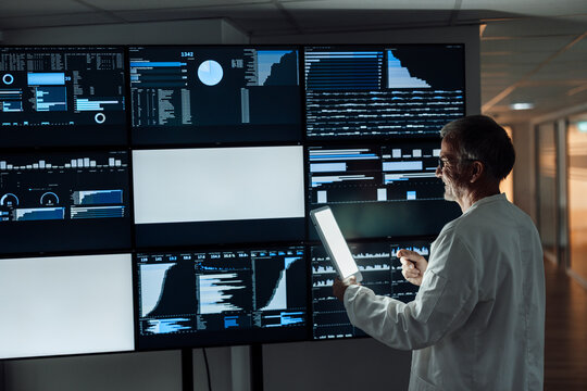 Doctor analyzing healthcare data on monitors in dark hospital