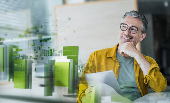 Smiling businessman with tablet in modern setting and green energy concept
