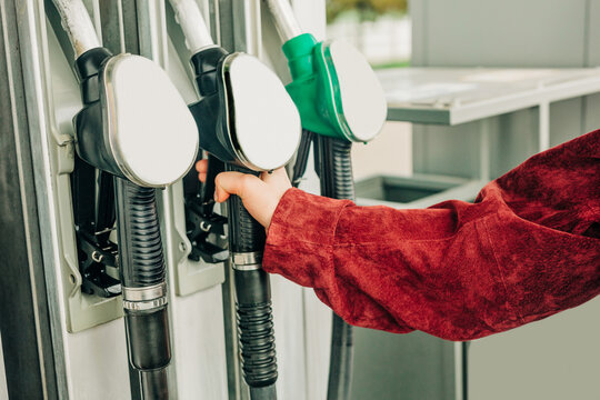 Hand holding fuel nozzle at gas station before refueling car