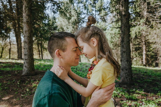 Girl and father face to face embracing each other in forest