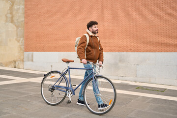 Fototapeta premium Young man walking a bicycle in urban setting