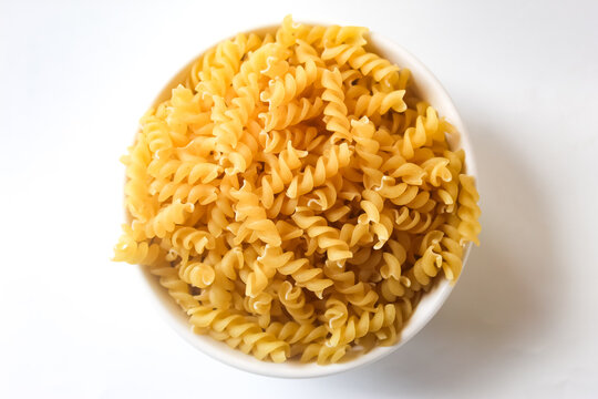 top view of fusilli pasta in a bowl on a white background