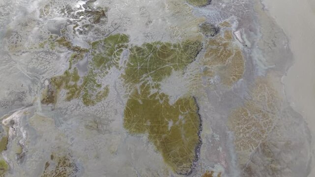 Aerial footage of coastal mudland islands and tidal channels showing vegetation and sediment patterns.