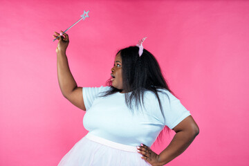 Fototapeta premium Image of a beautiful woman posing in a fairy costume on a pink background