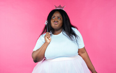 Fototapeta premium Image of a beautiful woman posing in a fairy costume on a pink background