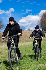 Obraz premium Two young cyclists enjoying a sunny day outdoors, riding their bikes across a grassy field.