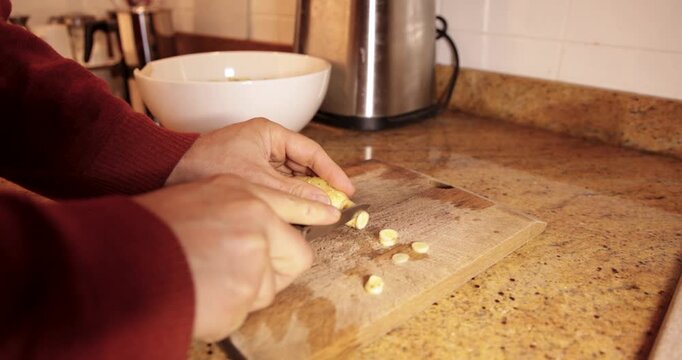 Person slicing fresh ginger root on cutting board