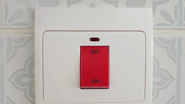 Finger pressing red on off switch on wall panel close up. Home electricity control and power toggle concept. Macro close up shot