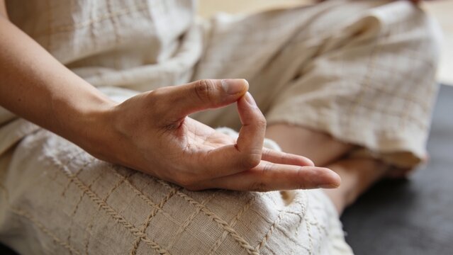 Close up of a hand in a gyan mudra gesture during a peaceful yoga meditation session.