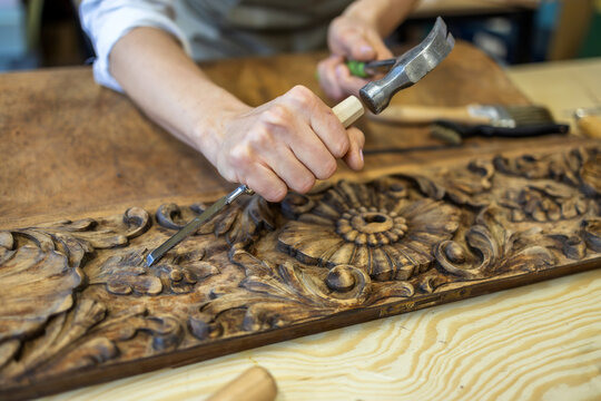 Restoring Ornate Wooden Panel with Carving Tools
