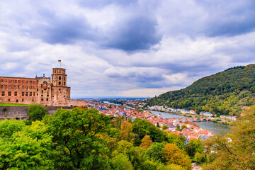 Fototapeta premium Heidelberg castle overlooks the river and town on a cloudy day in Germany with green trees in the foreground