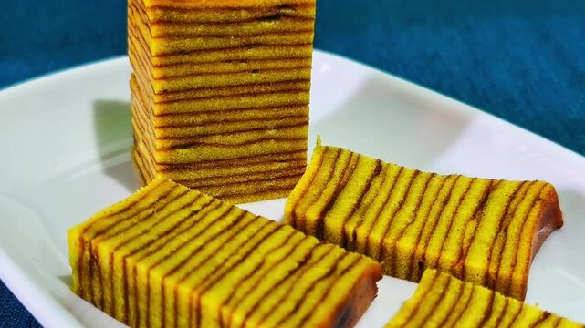 Slices of Indonesian Lapis Legit Layer Cake or Spekkoek on White Plate, Traditional Authentic Thousand Layers Spiced Butter Cake for Festive Celebration, Eid Al-Fitr, and Lunar New Year Photography.