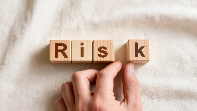 Hand Arranging Wooden Blocks to Spell 'Risk' on Fabric