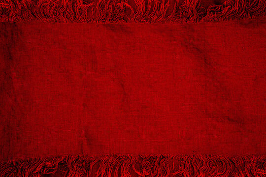 Bright red fabric with fringes laid out flat on a surface for textile presentation or creative use