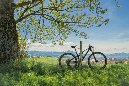 Bicycle parked on a hill overlooking Kempten and the Gruenten mountain, Allgau, Germany. Scenic view of the Alps with a mountain bike in the foreground under a blue spring sky. Active lifestyle.