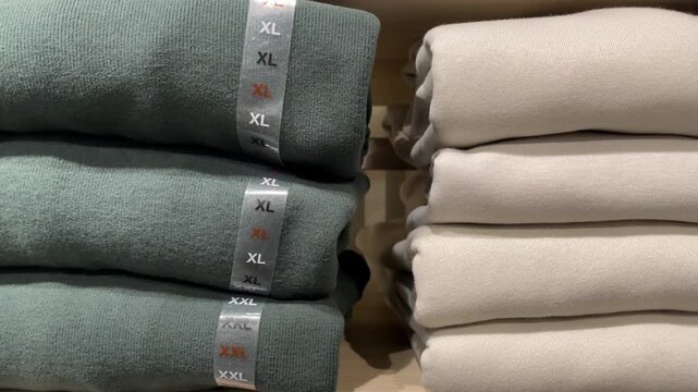 Folded sweaters stacked neatly in a store display showcasing XL size tags background