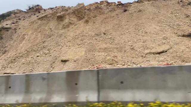 Landslide blocking road with rocks and debris, showing visible terrain erosion impact