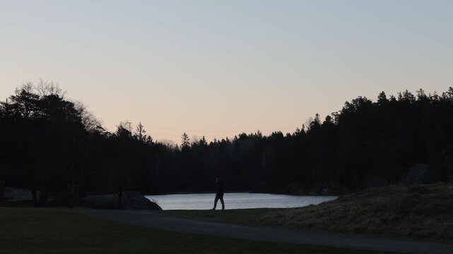 Stockholm, Sweden A man walks through the Nacka Reservatet wilderness in the early dawn past a small lake. 