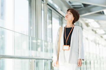 Fototapeta premium ガラスの通路を歩く30代ビジネス女性